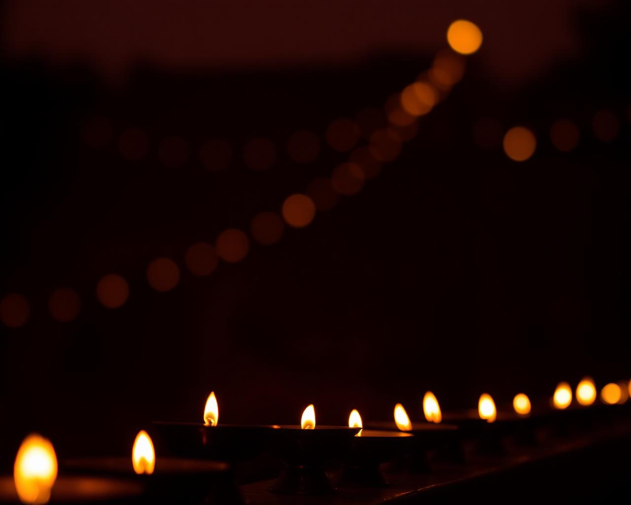 Rows of glowing brass diya lamps at dusk